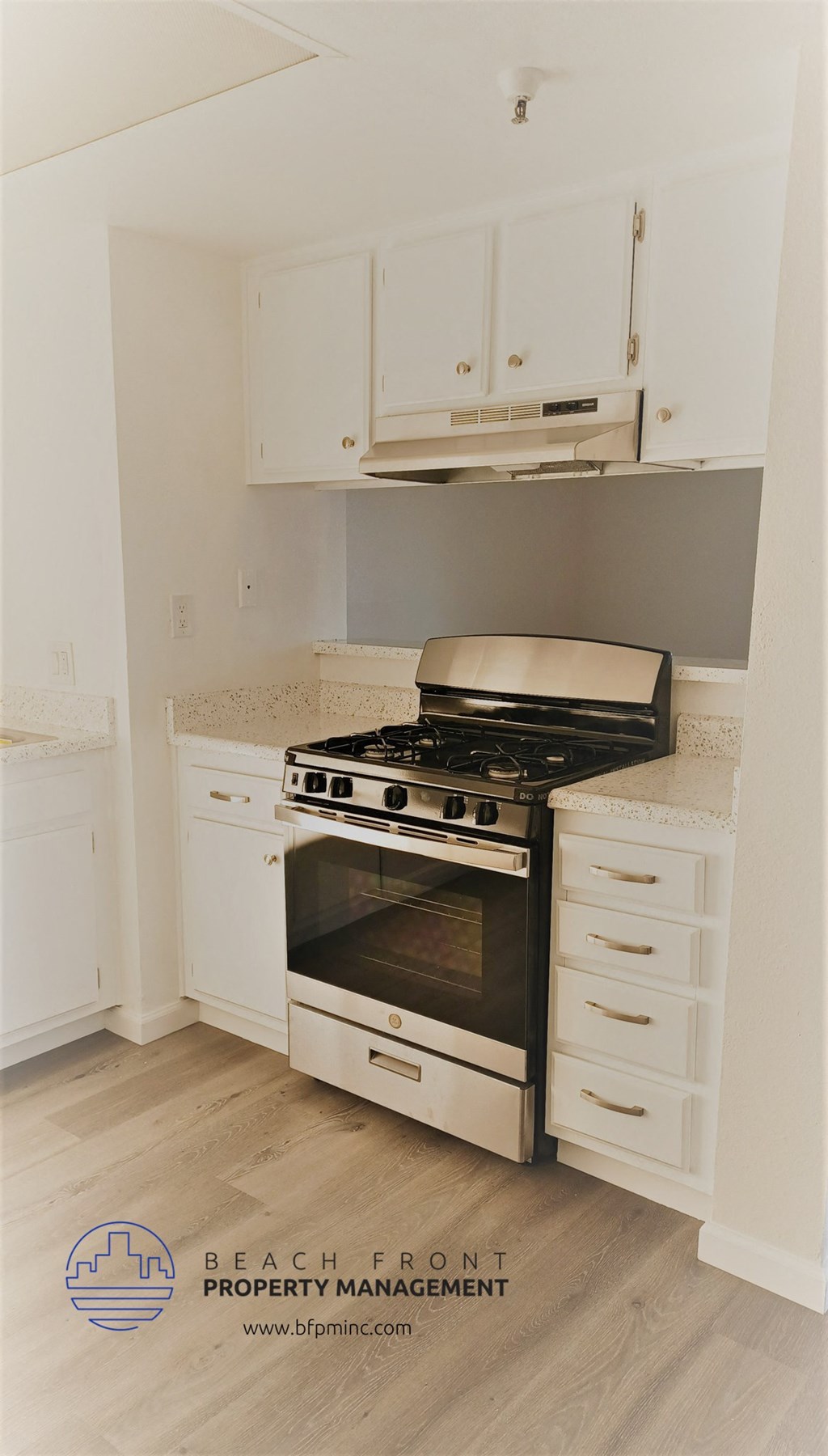 an empty kitchen with white cabinets and a stove and oven