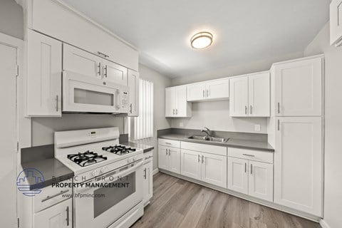 a kitchen with white cabinets and white appliances and a sink and a stove