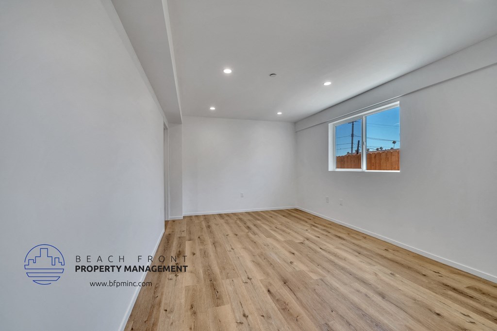 a room with white walls and wood flooring and a window