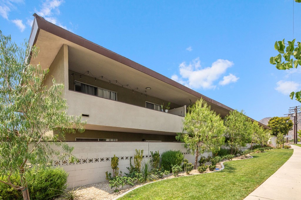 a house with a concrete facade and a yard with grass and trees