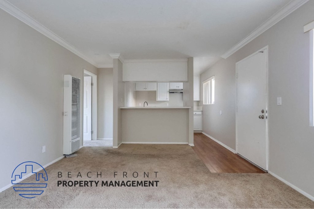 an empty living room and kitchen with white walls and wood flooring