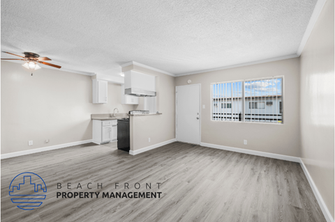 a living room and kitchen with wood flooring and a ceiling fan
