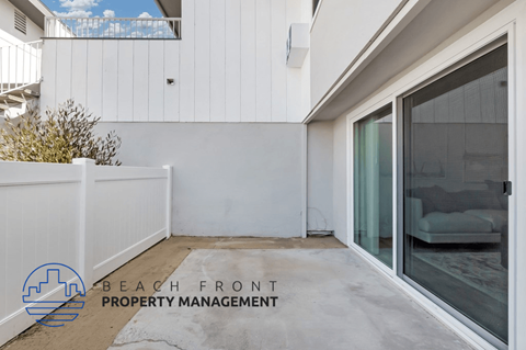 a patio in front of a white house with a glass door
