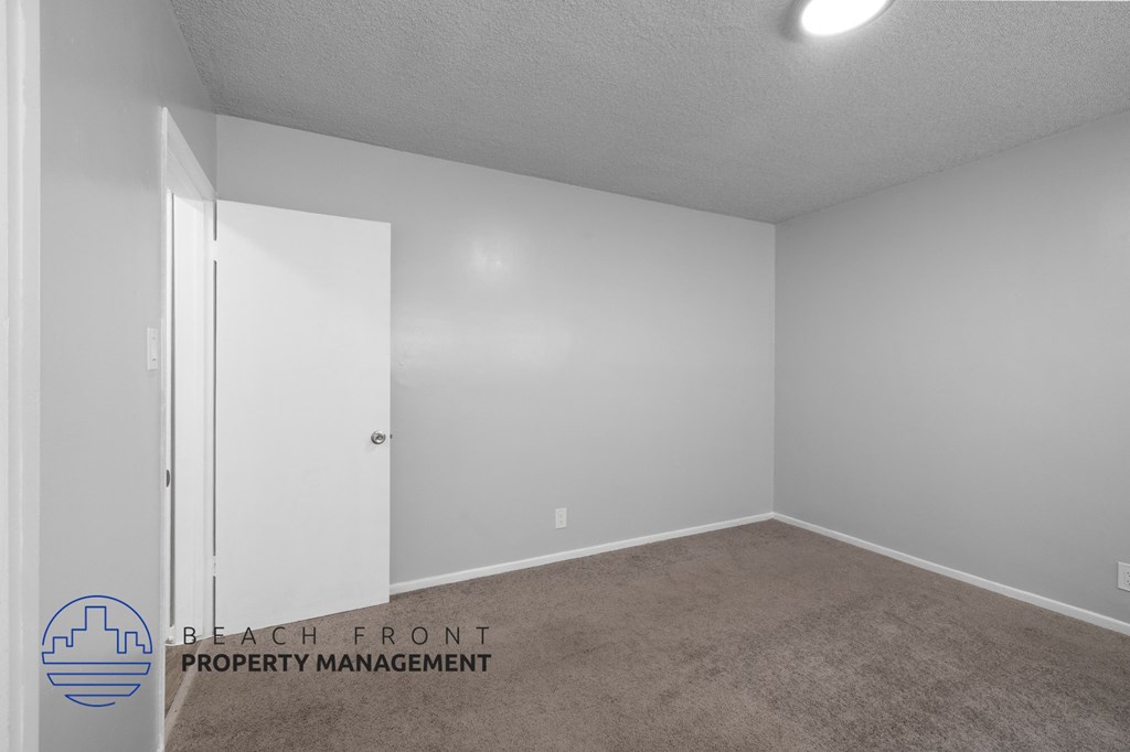 the spacious living room of an apartment with white walls and carpet