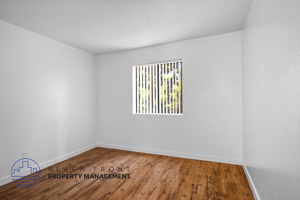 the living room of an apartment with wood floors and a window
