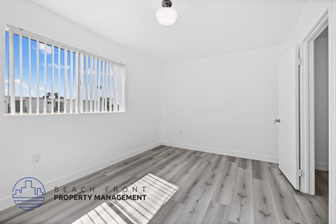 a living room with white walls and wood floors and a window