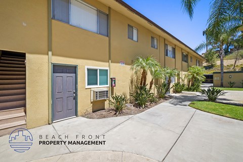 a sidewalk in front of a building with a purple door