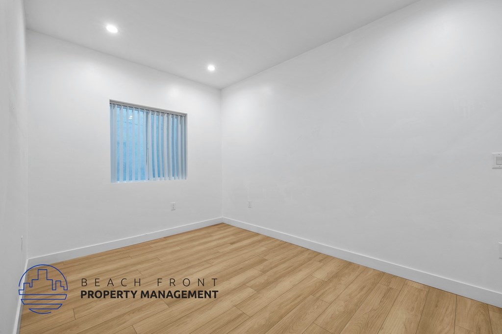 a living room with white walls and wood floors and a window