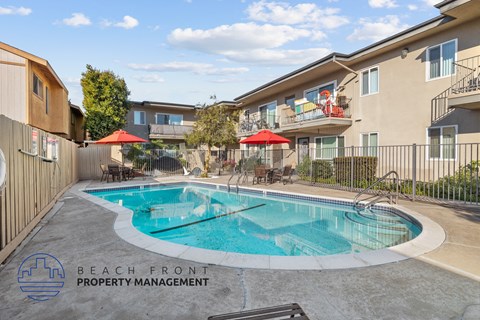 A pool surrounded by a fence and a bench with the words Beach Front Property Management.