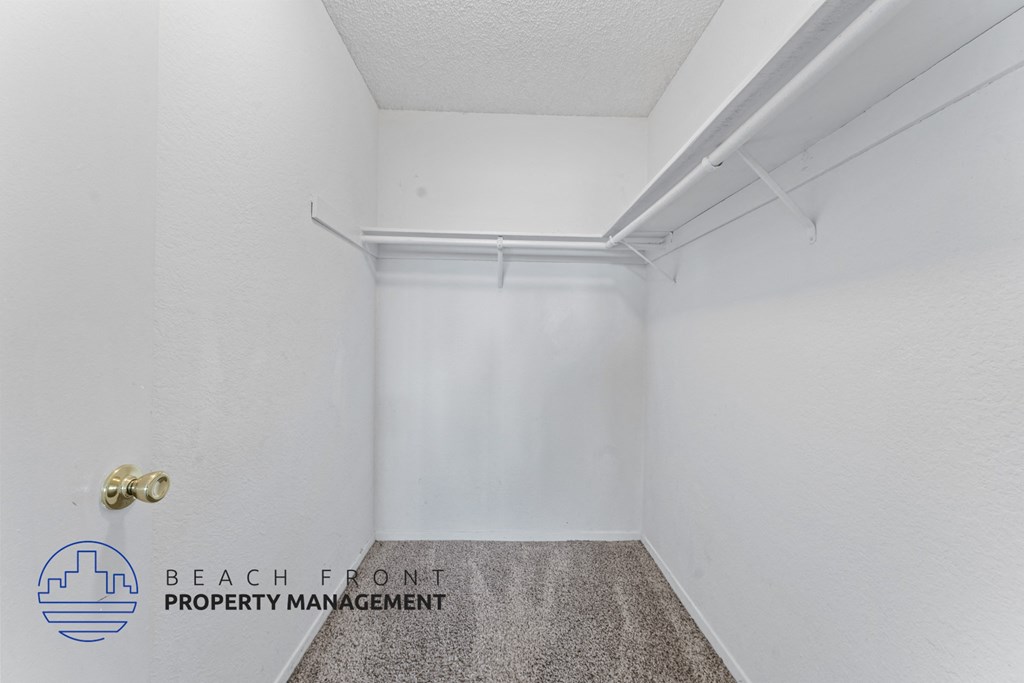 A white room with a carpeted floor and a door with a gold handle.