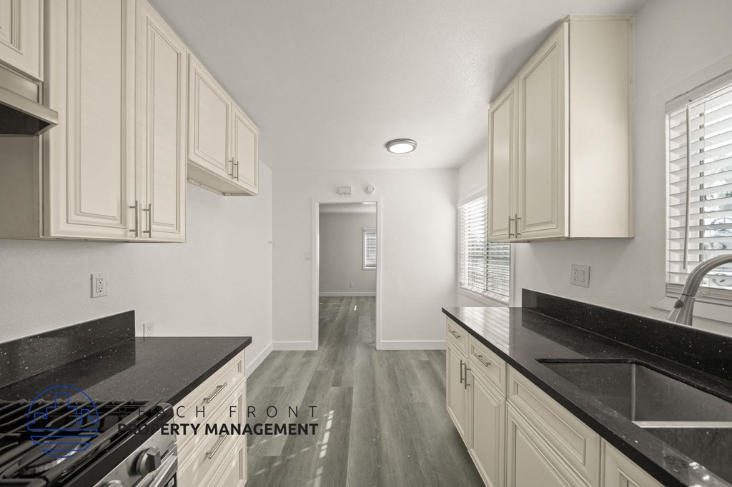 A kitchen with white cabinets and black countertops.