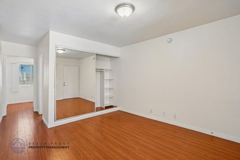 A spacious room with wooden floors and a large mirror.