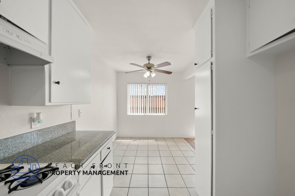 A kitchen with a white tile floor and a fan on the ceiling.