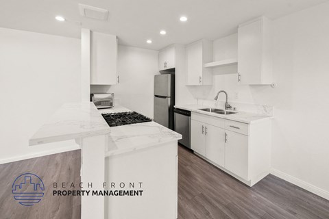 A kitchen with white cabinets and a wooden floor.