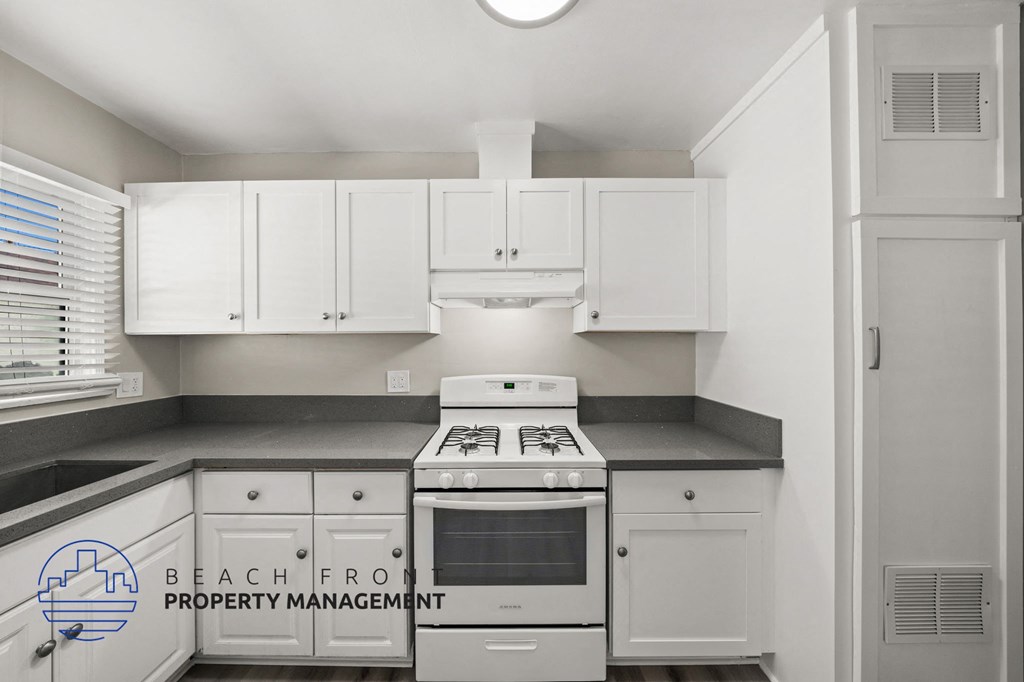 A kitchen with white cabinets and a stove top oven.