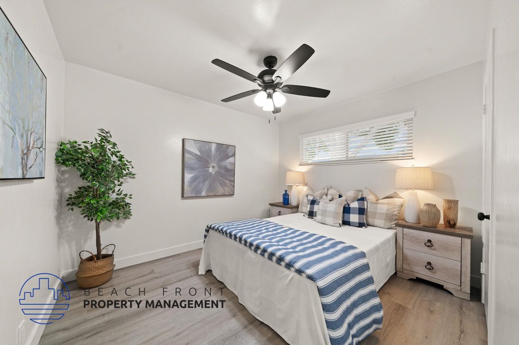 A bedroom with a bed, a ceiling fan, and a potted plant.