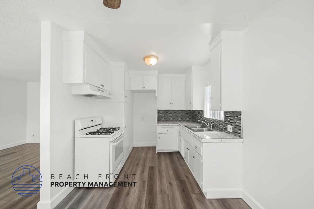 A kitchen with white cabinets and a wooden floor.