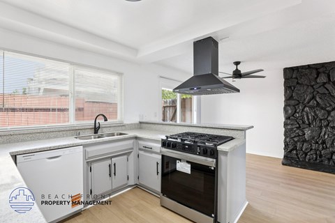 A modern kitchen with a stove top oven and a fan hood.