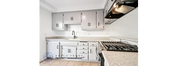 A kitchen with white cabinets and a stove top oven.