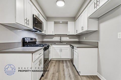 A kitchen with white cabinets and a stove top oven.