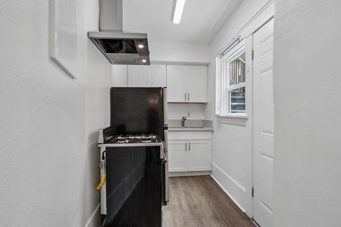 A black stove is in a white kitchen with wood floors.