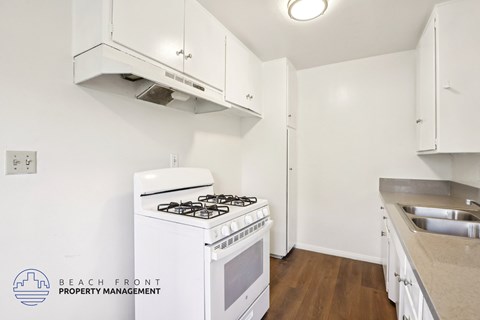 A kitchen with a white stove and cabinets.