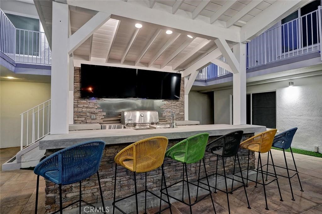 a bar with colorful chairs in front of a kitchen with a television