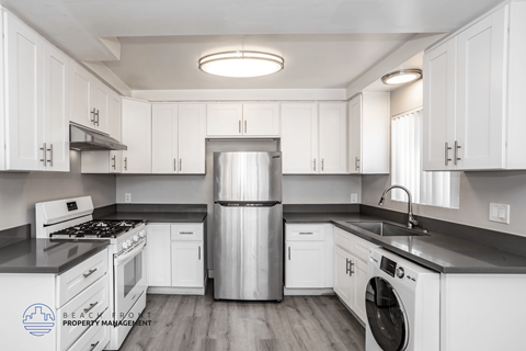 A kitchen with white cabinets and a stainless steel refrigerator.