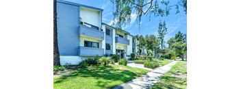 a white and grey apartment building with a sidewalk in front of it