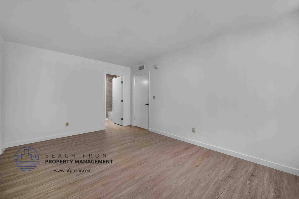 a bedroom with hardwood floors and white walls