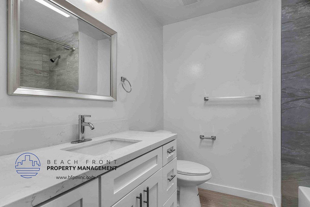 a bathroom with a white sink and toilet and a shower with a glass door