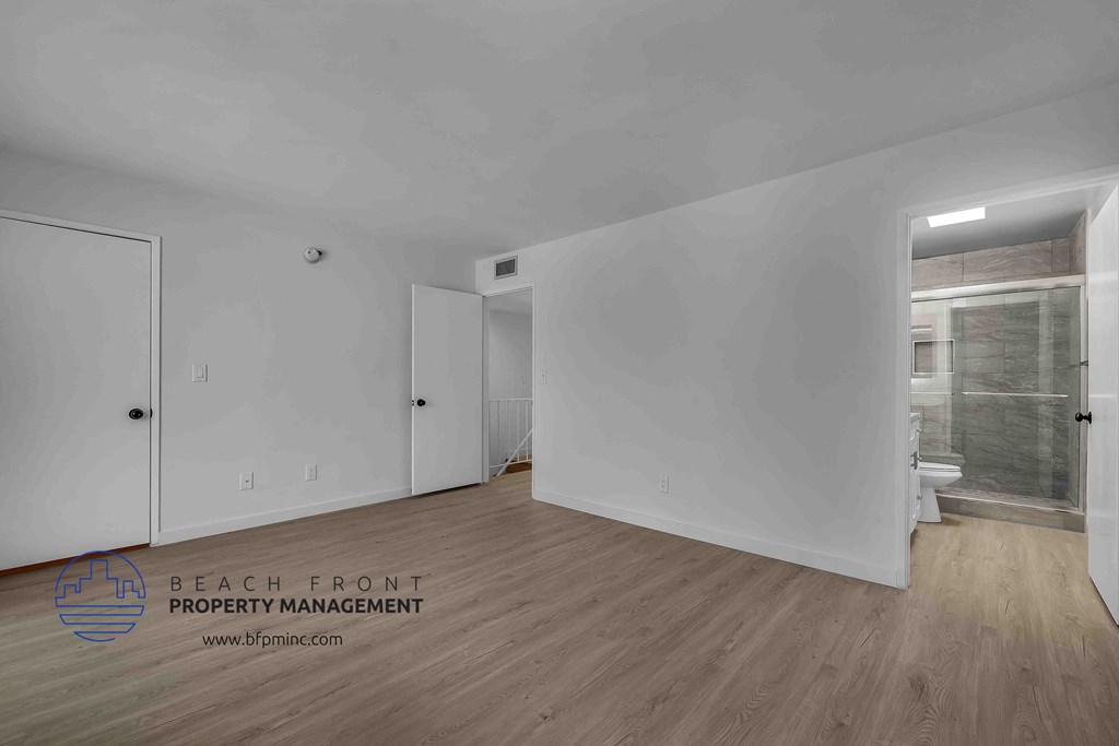 a bedroom with hardwood floors and white walls