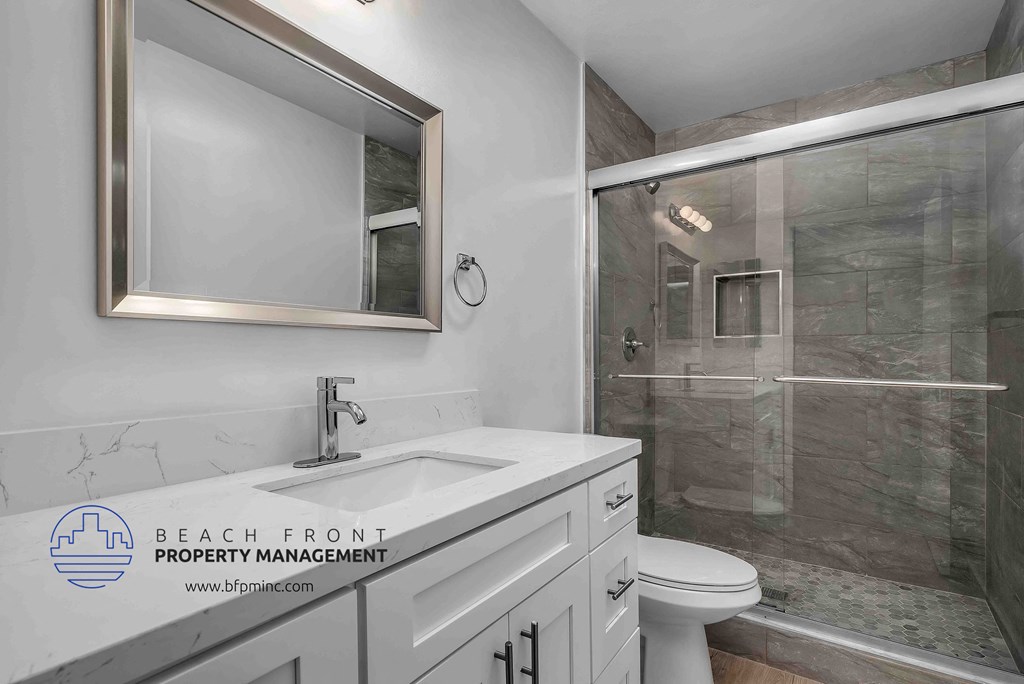 a bathroom with a white sink and toilet next to a shower with a glass door
