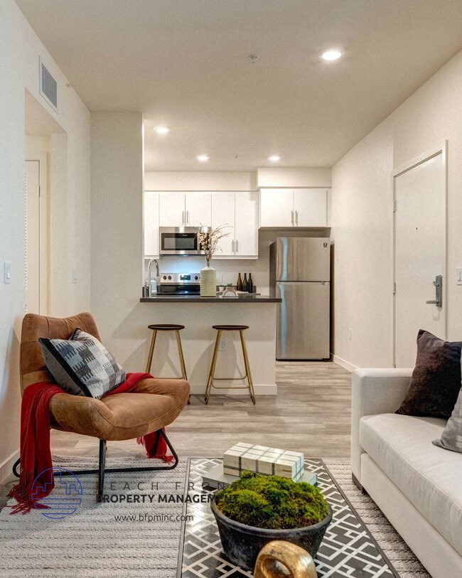 a living room with a couch and a chair in front of a kitchen