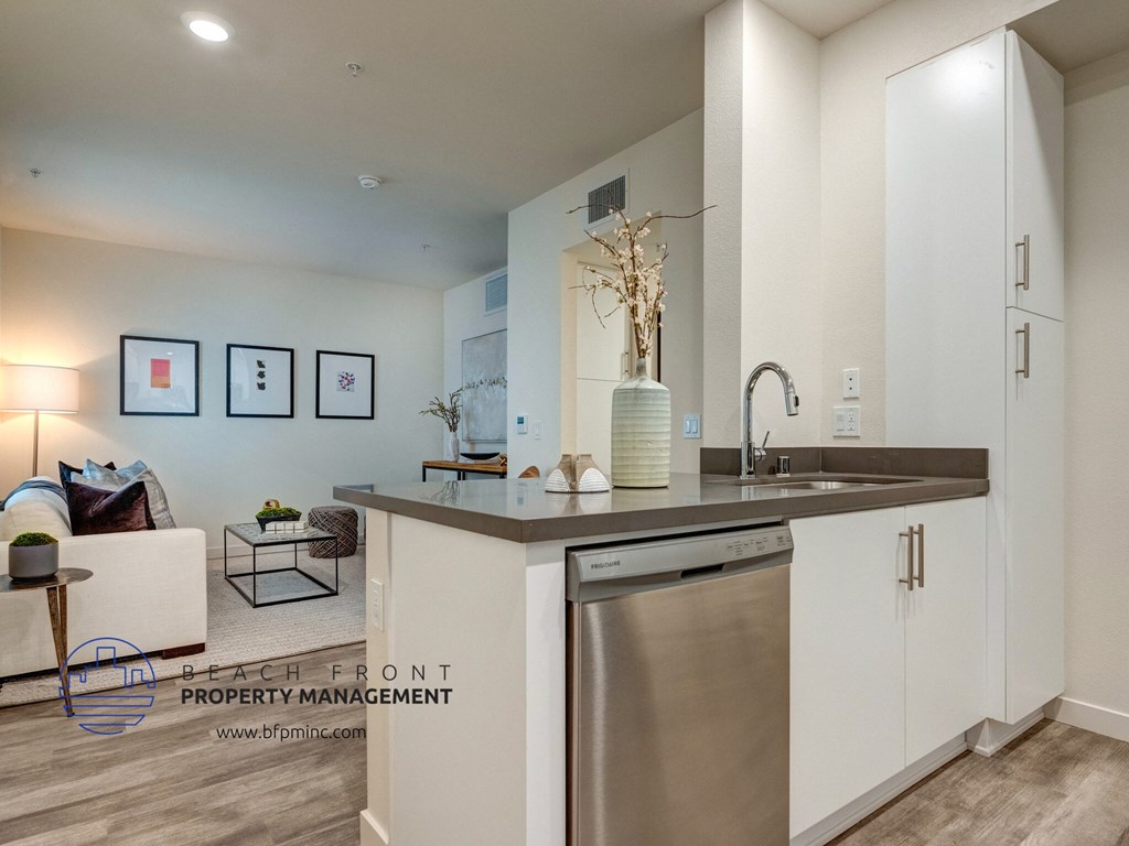 a kitchen with a sink and a dishwasher next to a living room