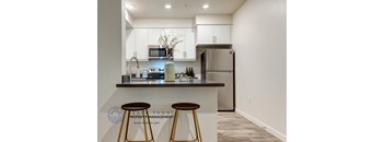 A modern kitchen with a bar stool in front of it.
