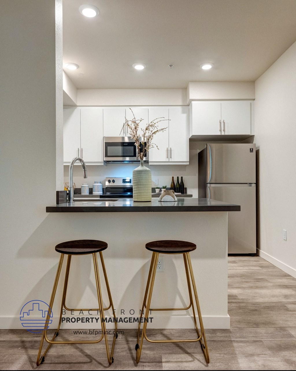 a kitchen with white cabinets and a counter top with two stools