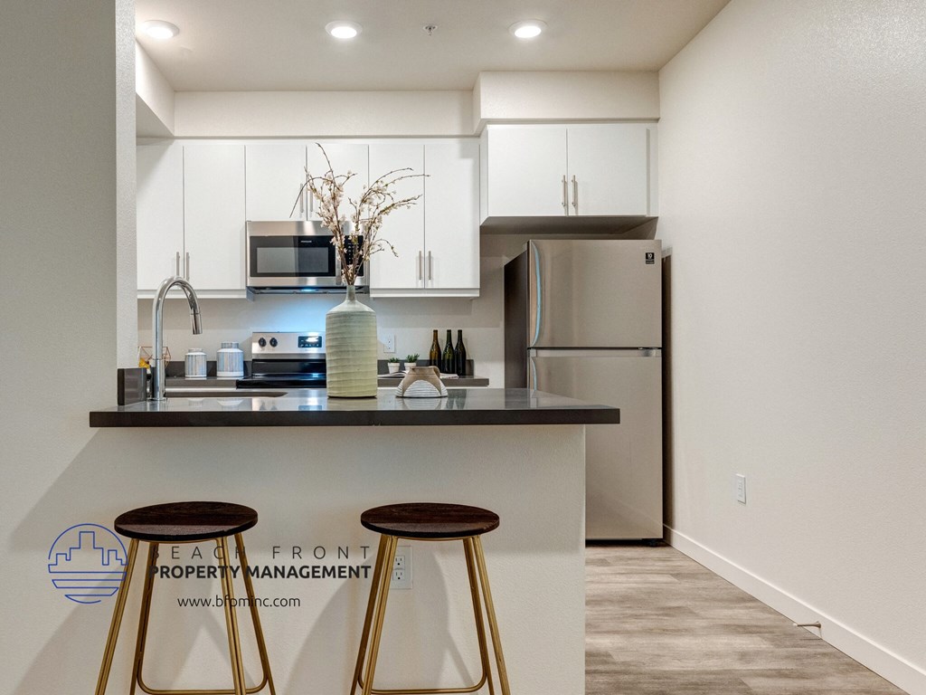 a kitchen with stools and a counter with a sink and refrigerator