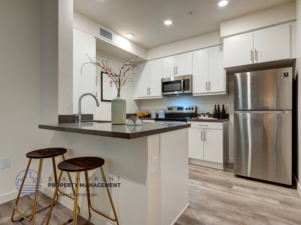 a kitchen with stainless steel appliances and a counter with two stools