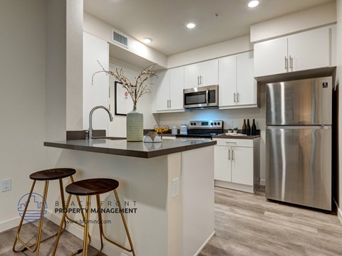 A modern kitchen with a bar stool and a stainless steel refrigerator.