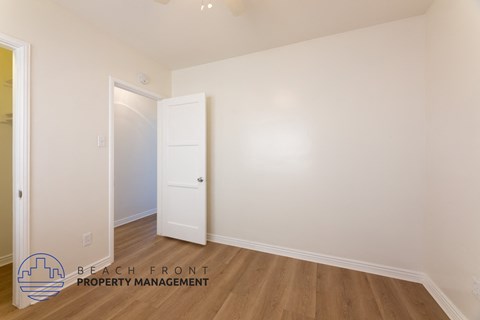 a bedroom with white walls and wood floors and a white door