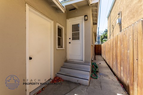 the front door of a house with stairs and a fence