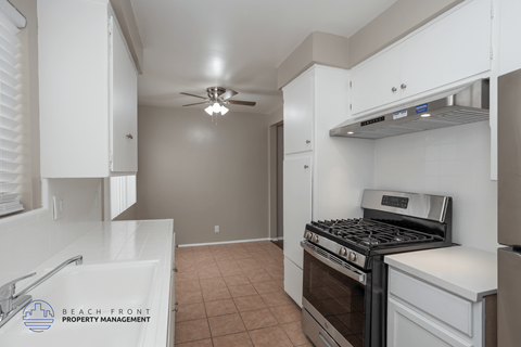 A kitchen with a stove top oven and a fan ceiling light.