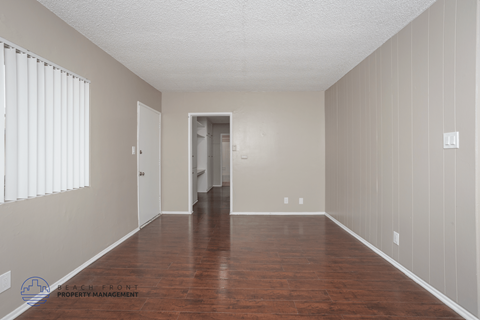 A spacious room with wooden floors and white walls.