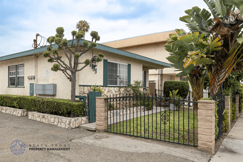 A house with a green fence and a tree in front.