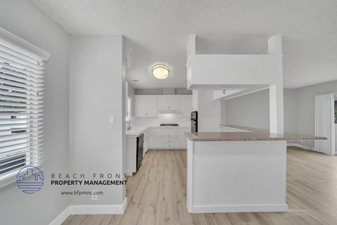 a white kitchen with hardwood floors and white cabinets