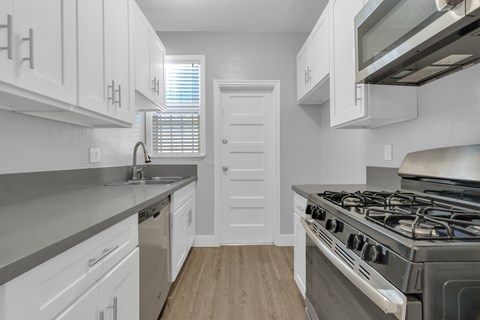 A kitchen with white cabinets and a stainless steel stove.