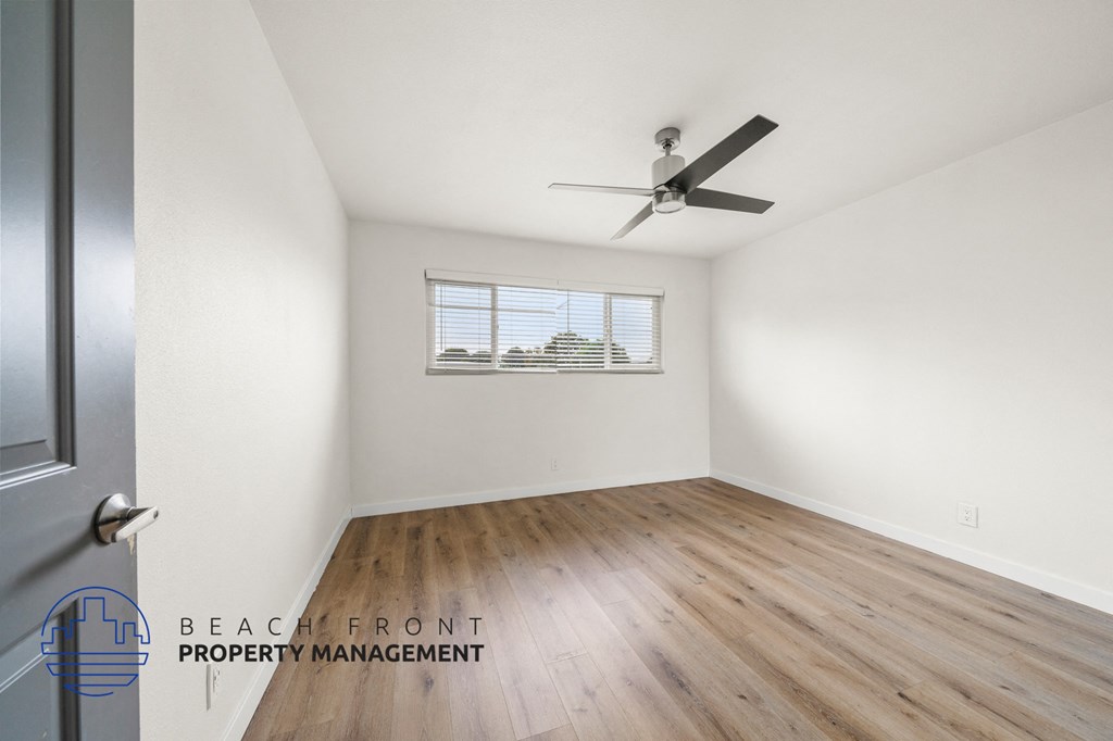 A room with a ceiling fan and wooden flooring.