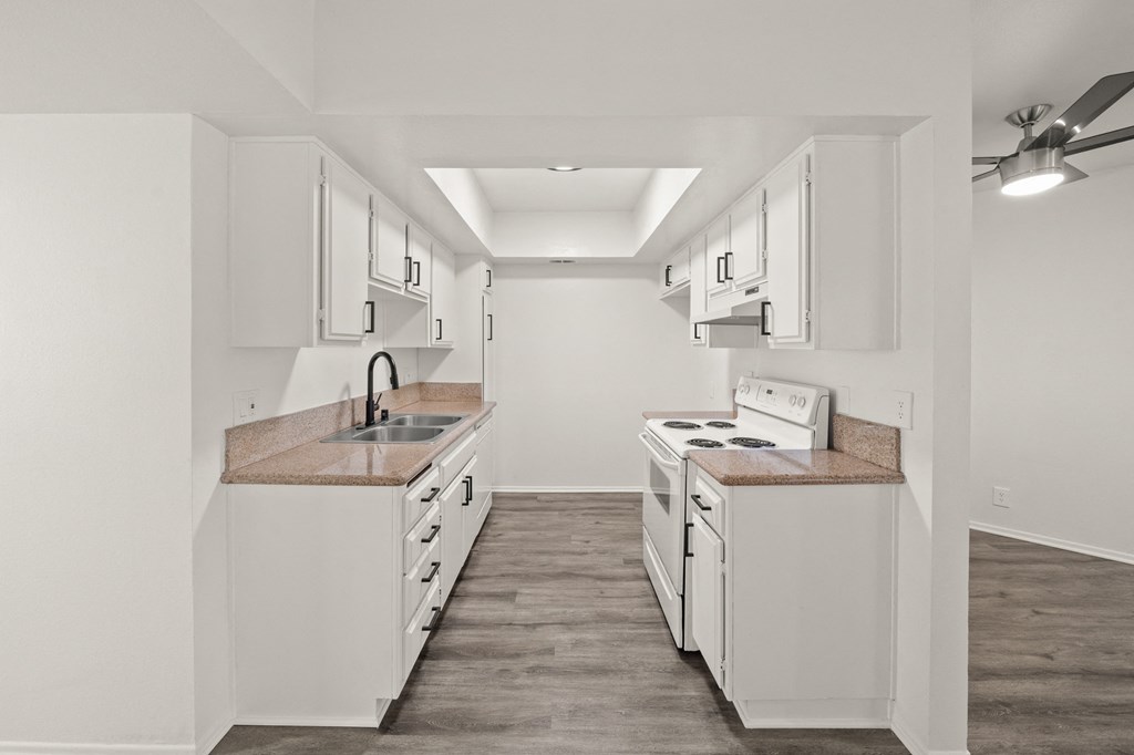 an empty kitchen with white cabinets and white appliances and a sink and a stove