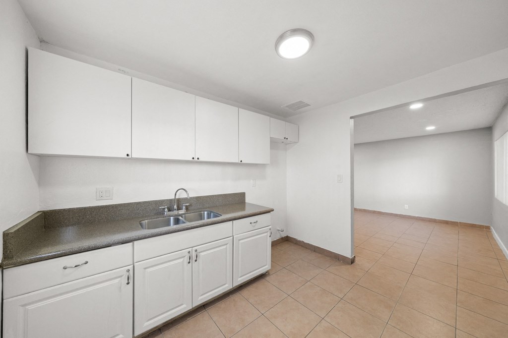 an empty kitchen with white cabinets and a sink